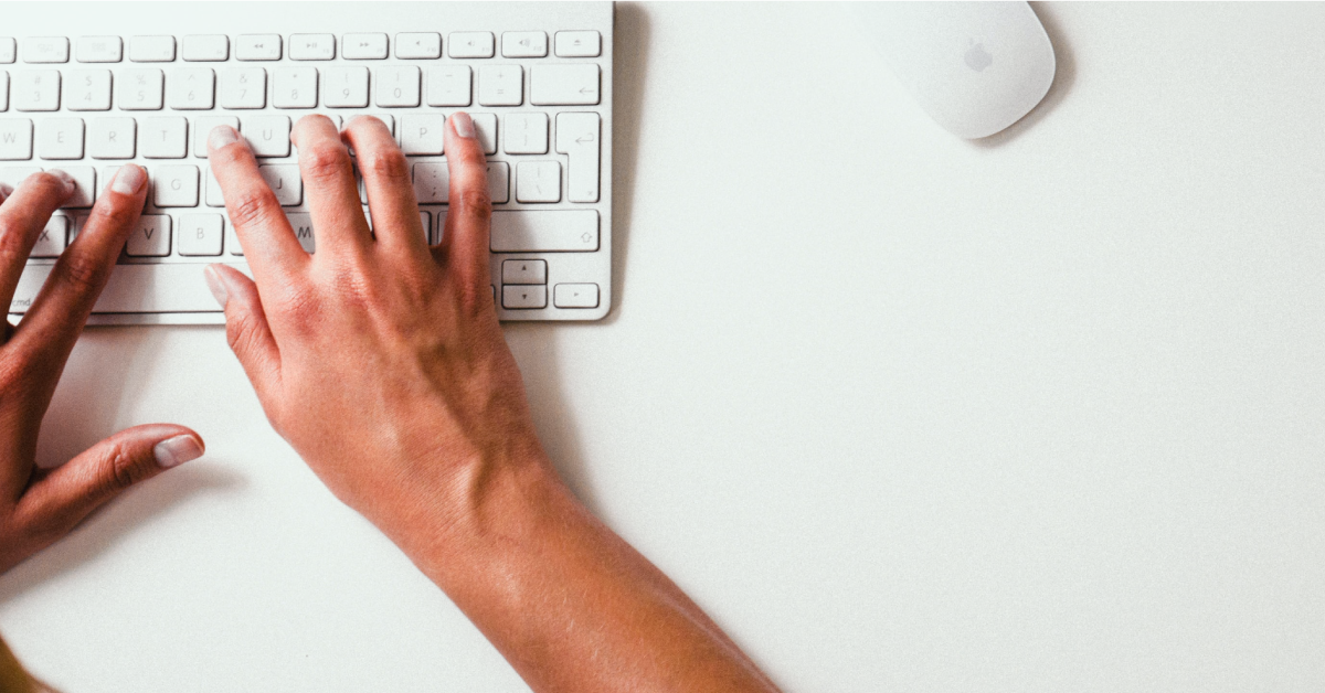 Hands typing at a computer keyboard.