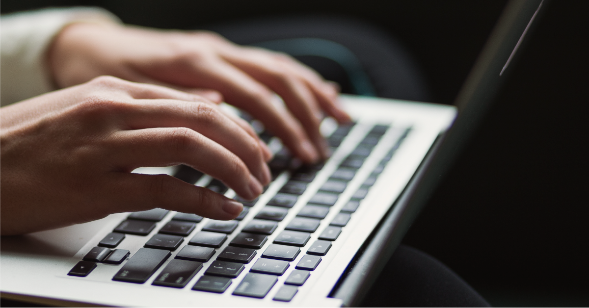 Hands typing on a laptop keyboard. 